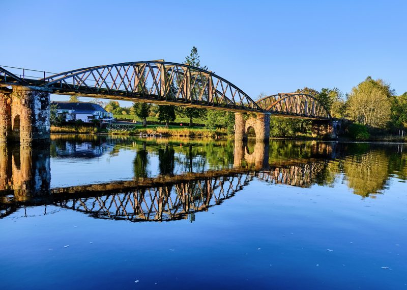 A picturesque view of an old bridge reflected in Loch Ken in Scotland