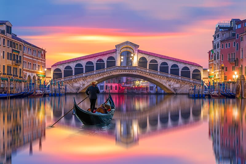 A gondolier sails towards the Rialto Bridge in Venice, Italy