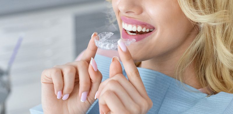 A woman holding clear aligners